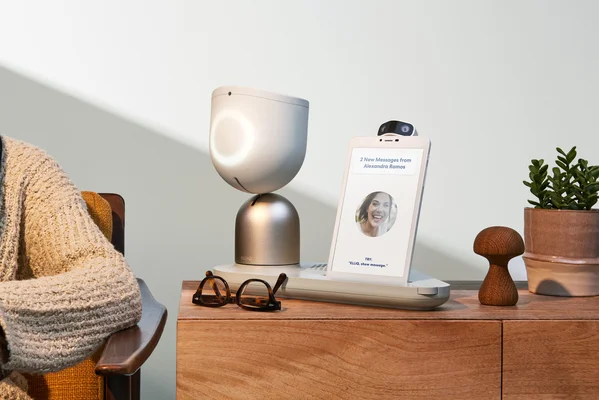 Le robot ElliQ posé sur un buffet en bois avec ses accessoires quotidiens.