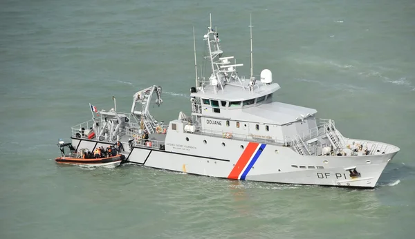 Bateau des Douanes françaises avec un canot de sauvetage orange lors d'une opération d'assistance au large du Pas-de-Calais.