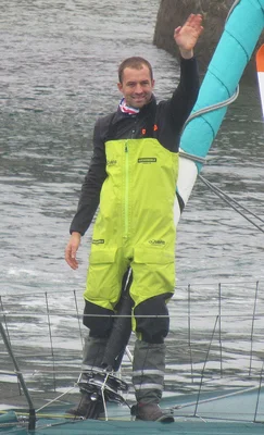 Sam Goodchild à bord de son voilier, vêtu d'un équipement de voile jaune et noir.