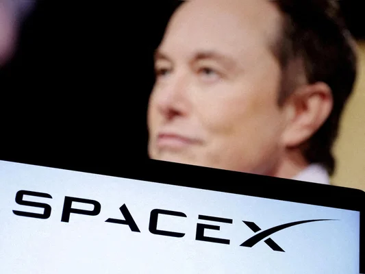 Elon Musk derrière un écran montrant le logo de SpaceX.