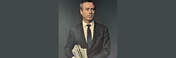 Lionel Barber en costume rayé, tenant un journal.