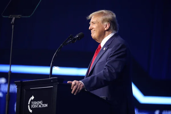 Donald Trump posant devant un fond de rideaux dorés.