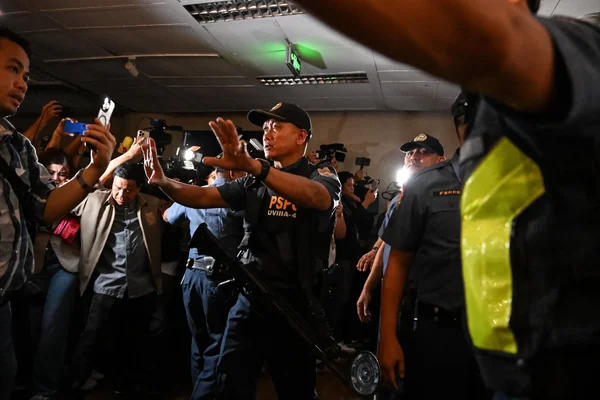 Agent de sécurité gérant la foule de journalistes au Sénat philippin.