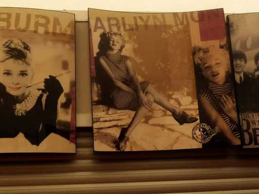 Affiches sépia d'Audrey Hepburn et Marilyn Monroe sur une étagère, symboles du cinéma classique.