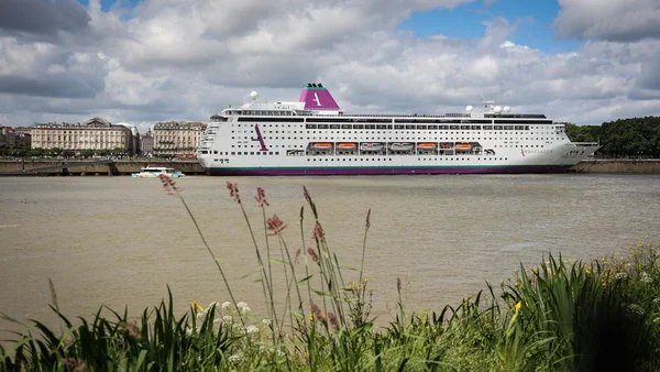 Le paquebot Ambition (Ambassadeur) naviguant sur un fleuve, avec des immeubles en arrière-plan.