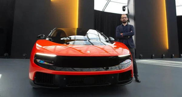 Un homme pose devant une Ferrari SF90 Spider lors d'une présentation sur scène.