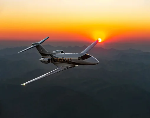 Un Pilatus PC-24 en vol au-dessus des montagnes au coucher du soleil.