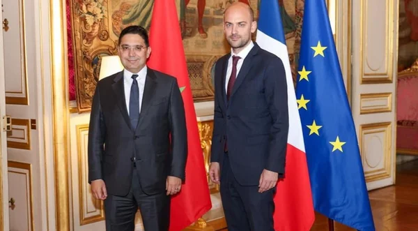 Nasser Bourita et Jean-Noël Barrot devant les drapeaux marocain, français et européen.