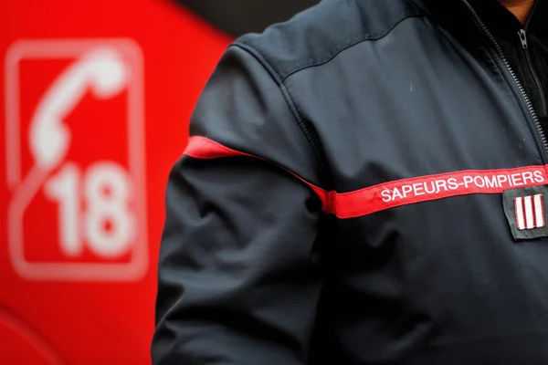 Un pompier en uniforme avec le numéro d’urgence 18 en arrière-plan.