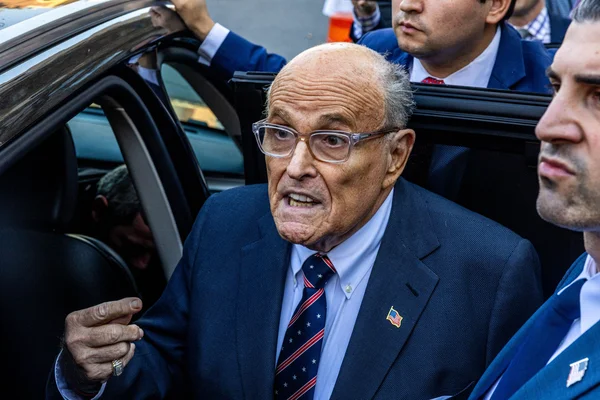 Rudy Giuliani sortant d'une voiture après un accident, entouré de son équipe.