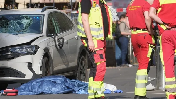 Une voiture blanche endommagée et un corps couvert d'une bâche bleue à Leipzig, des secouristes sur place.