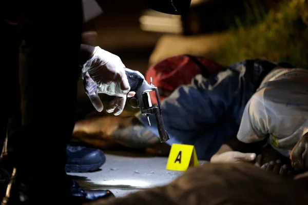 Scène de crime avec un revolver et un corps sous un marqueur jaune 'A', illustrant les violences liées à la guerre contre la drogue aux Philippines.