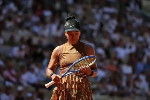 Naomi Osaka en robe brune et visière noire sur le court Suzanne-Lenglen.