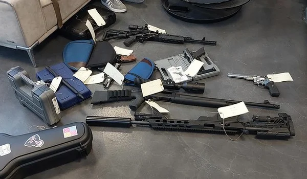 Armes saisies par les agents des douanes chez un particulier, présentées avec des étiquettes d'inventaire.