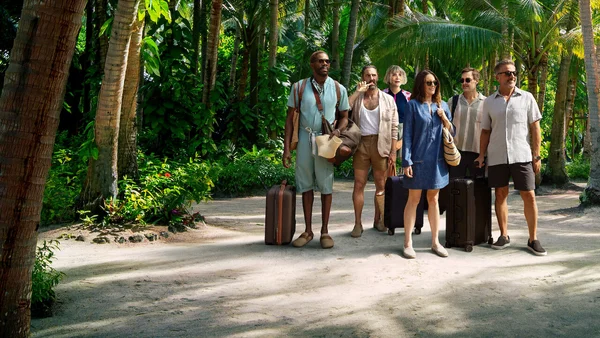 Groupe de six personnes sur un chemin sablonneux dans un décor tropical, bagages en main, évoquant l'arrivée dans un lieu de villégiature.