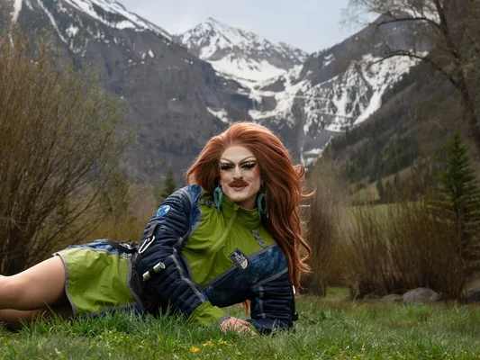 Pattie Gonia posant dans un décor de montagne enneigée, vêtue d'une veste North Face
