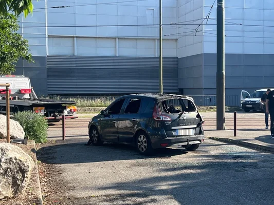 Véhicule endommagé, une Renault Scenic, stationné à côté d'une dépanneuse.