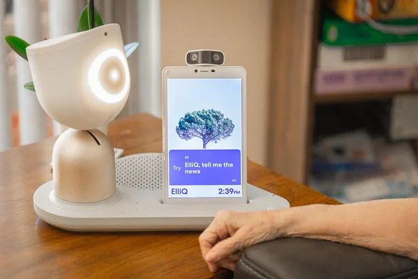 ElliQ et sa tablette, utilisés par une personne âgée à son domicile.