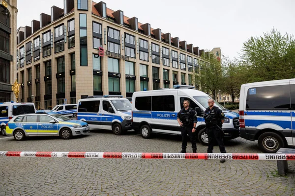 Des policiers devant le grand magasin Breuninger à Leipzig, ruban de police au premier plan.