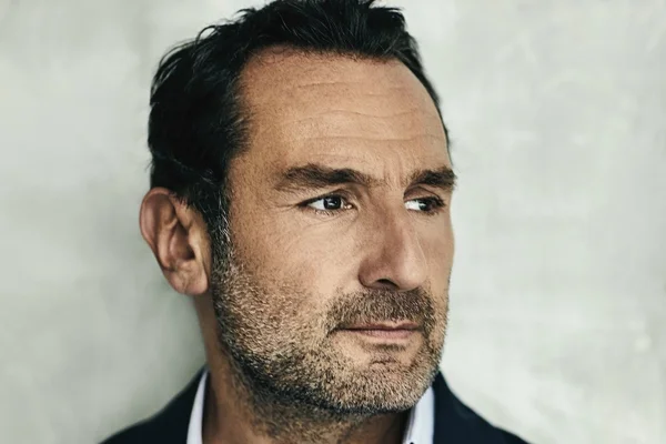 Gilles Lellouche, gros plan sur fond gris clair.