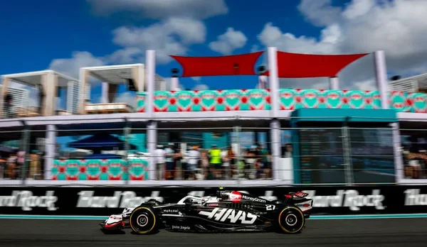 Une monoplace de F1 passe devant le mur Hard Rock et les tribunes colorées du circuit de Miami.