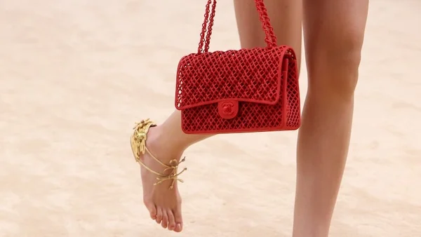 Accessoires Chanel comprenant un sac à main rouge tressé et des sandales dorées.