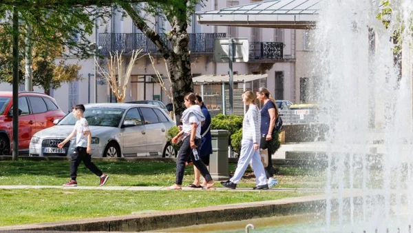 Promeneurs dans un parc ensoleillé, cherchant à se rafraîchir près d'une fontaine.