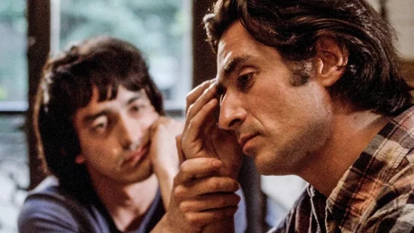 Scène du film 'Plus forts que le diable' : deux hommes dans une pièce, l'un en chemise à carreaux, l'autre en arrière-plan.