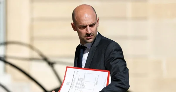 Le chef de la diplomatie française, photographié en extérieur avec un dossier rouge.