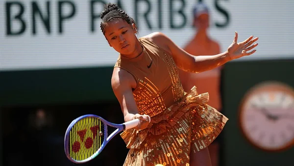 Naomi Osaka en pleine action sur le court, vêtue d'une robe à sequins marron, lors de son match à Roland-Garros.