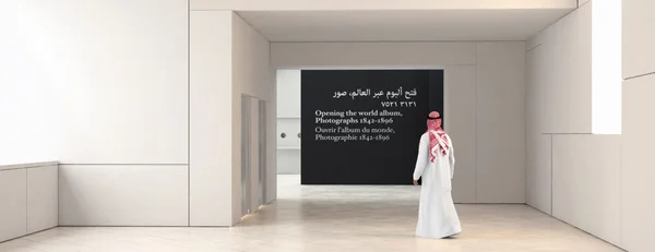 Visiteur dans une galerie du Louvre Abu Dhabi, face à un panneau d'exposition trilingue.