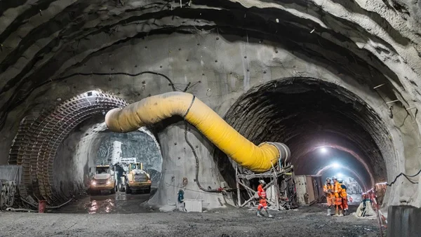 Intérieur du chantier Lyon-Turin avec deux galeries et des ouvriers en sécurité.