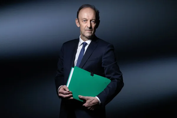 Vincent Duclert tenant un dossier vert, portrait studio.