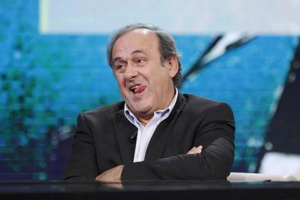 Michel Platini, assis à une table, réagit lors d'un entretien.