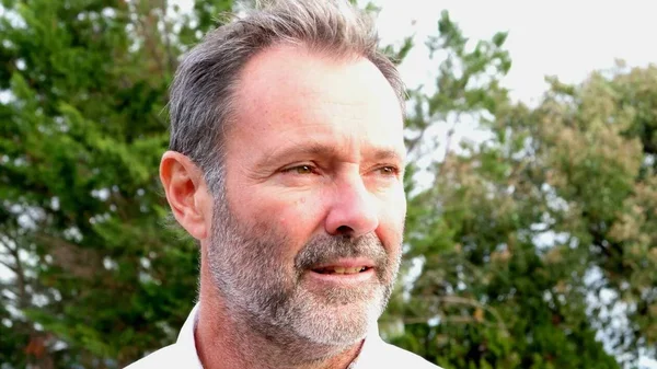 Christophe Cassou, climatologue, en extérieur devant des arbres.