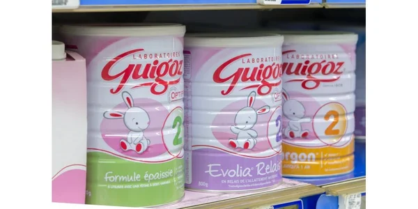 Boîtes de lait infantile Guigoz 2e âge sur une étagère.