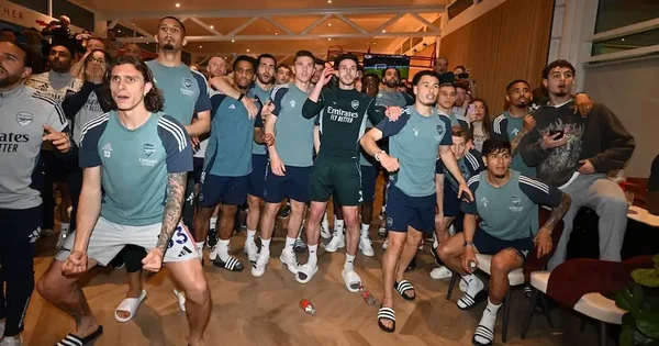 Joueurs d'Arsenal en tenue d'entraînement posant et dansant en intérieur.