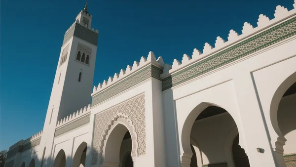 La Grande Mosquée de Paris vue de l'extérieur, façade blanche avec minaret sous un ciel bleu, lumière du matin