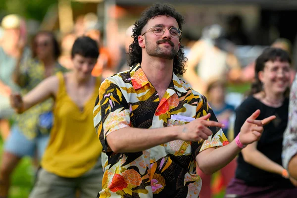 Un participant dansant au festival de la coupe mulet à Mons, arborant une chemise fleurie.