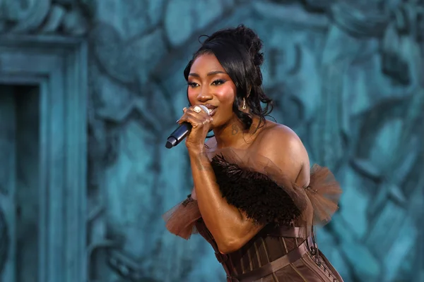 Aya Nakamura sur scène, dans une robe marron à plumes et tulle.