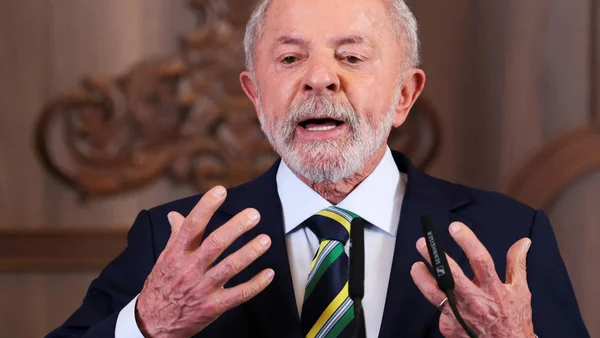 Poignée de main entre Donald Trump et Lula devant les drapeaux des États-Unis et du Brésil.