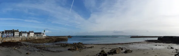 Vue panoramique de l'île de Sein avec le phare Men Brial, la plage et les côtes bretonnes au loin.