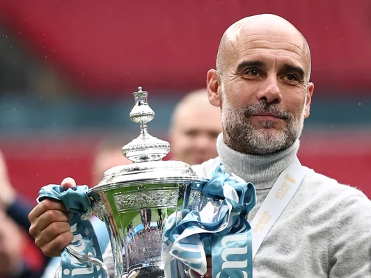 Pep Guardiola brandissant le trophée de la Premier League.