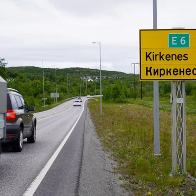 Route norvégienne E6 avec panneau bilingue vers Kirkenes, illustrant la fermeture des frontières aux voitures russes.