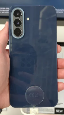 Le dos du Samsung Galaxy A57 en bleu navy, avec son triple capteur photo et une dragonne de sécurité.