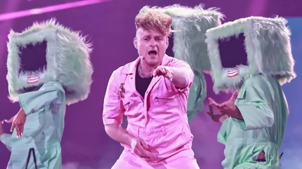 Look Mum No Computer, le candidat britannique à l'Eurovision, vêtu d'une combinaison rose, chante sur scène avec ses danseurs en costumes verts.
