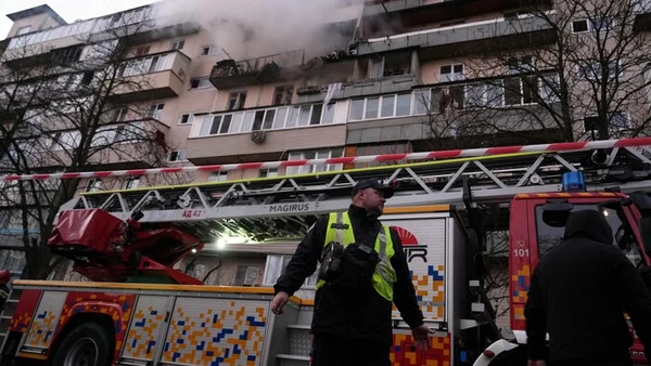 Pompier intervenant près d'un immeuble résidentiel en feu à Kiev après une attaque russe massive.