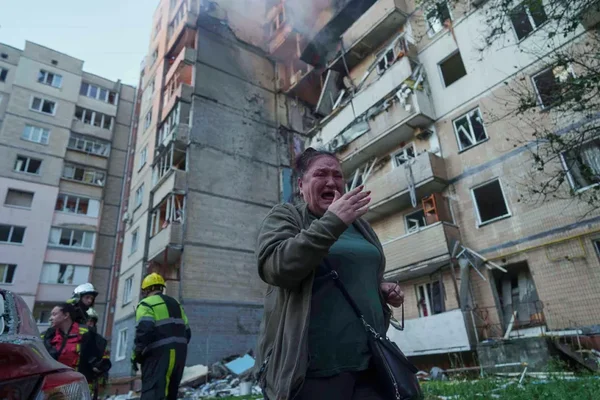 Femme en pleurs devant un immeuble résidentiel endommagé à Kiev après une attaque russe massive.