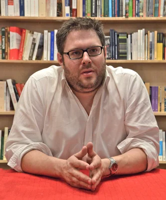 Mathieu Bock-Côté assis devant des bibliothèques.