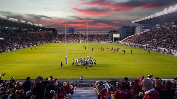 Un match de rugby au Stade Mayol de Toulon sous un ciel de coucher de soleil spectaculaire, avec des tribunes combles.